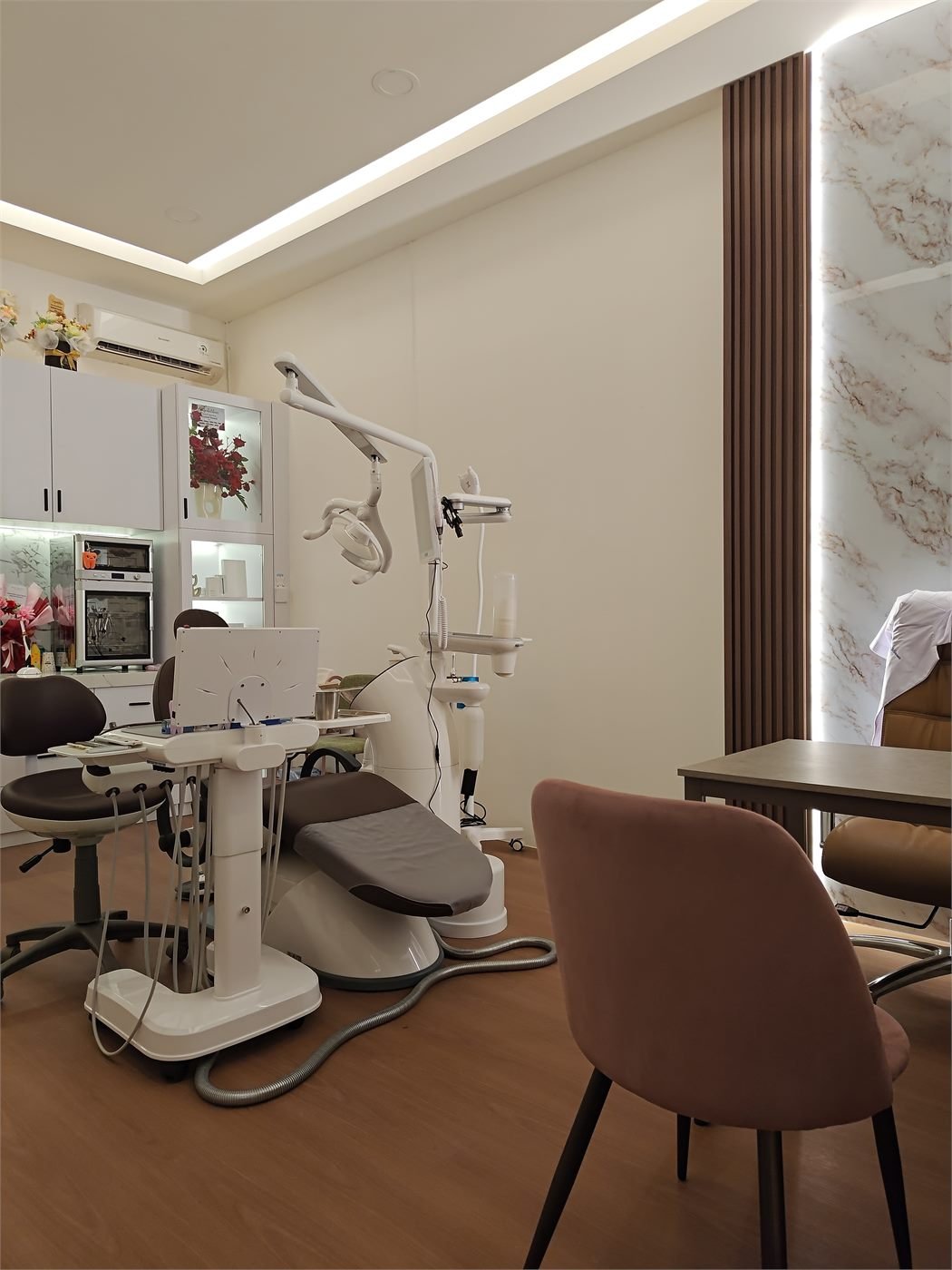 Ruang perawatan dengan kursi dental Osstem, lampu sorot, dan lemari instrumen