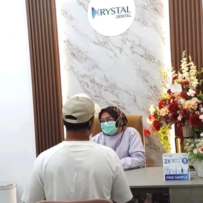 A patient discussing treatment with a dentist at the Krystal Dental front desk